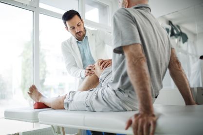 Arzt untersucht Knie bei Patient